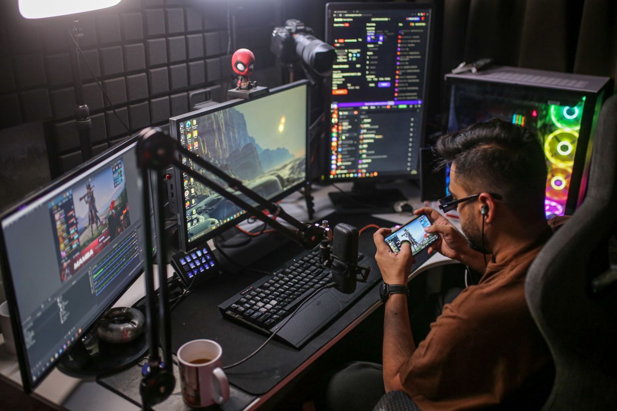 A creator streaming a mobile game from a multi-monitor setup