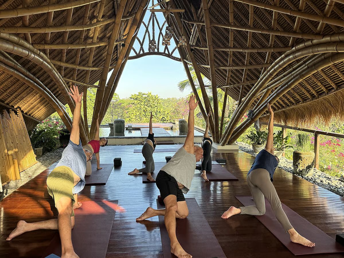 A yoga class under a bamboo pavilion opening onto a garden